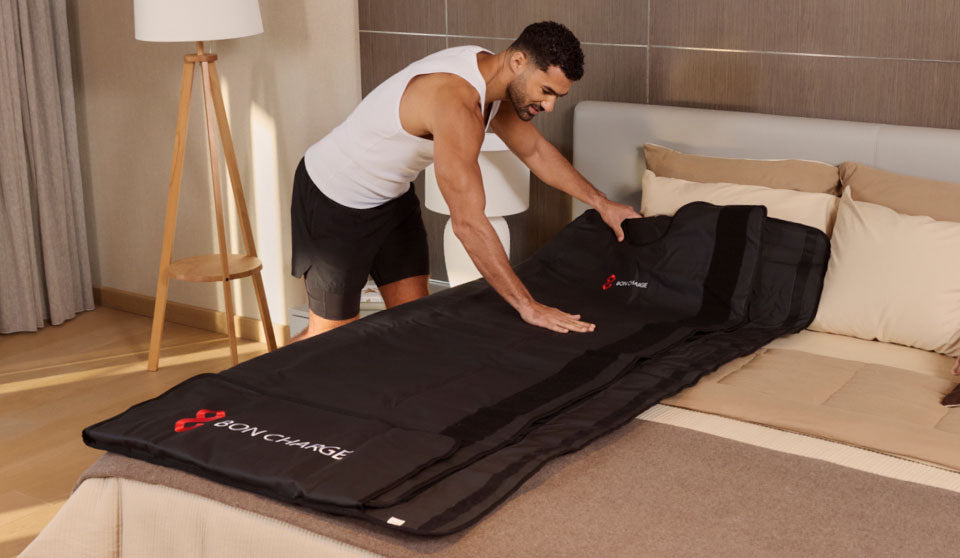 Man rolling out and setting up sauna blanket on bed